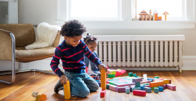 Two children playing with blocks on an apartment floor 