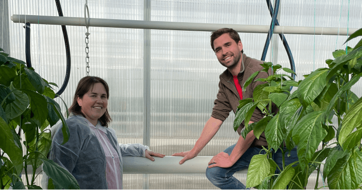 Two people are smiling and enjoying the pleasant atmosphere at the Under Sun Acres Inc. greenhouse.