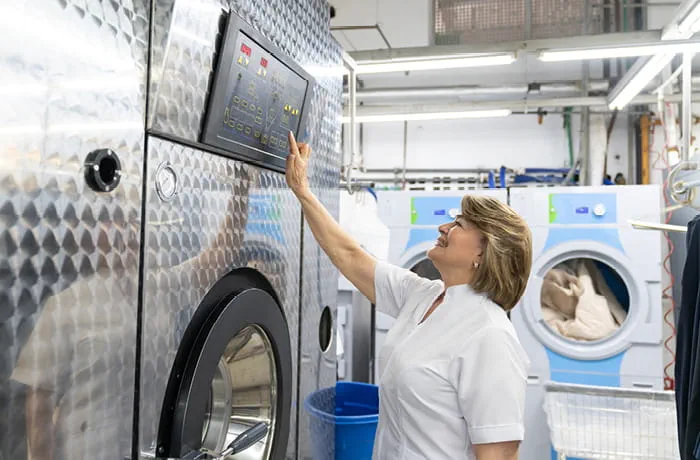Woman operating industrial washing machine