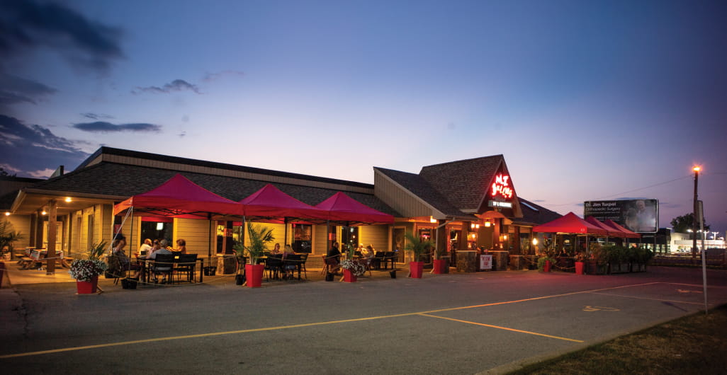 The exterior of a busy restaurant with a large patio at night