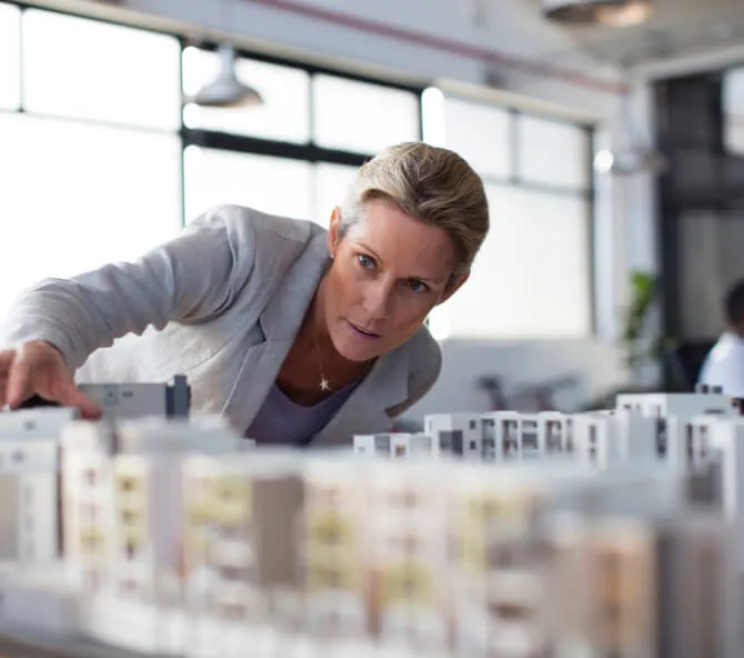 Woman leaning over table examining architectural model