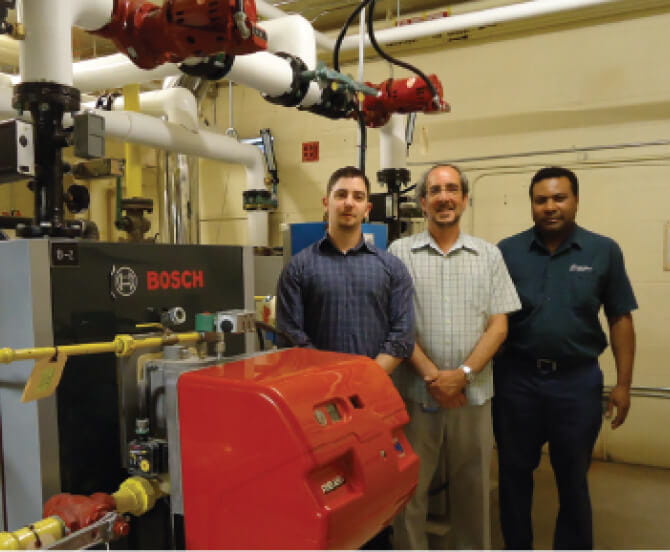 Three men standing beside boiler room equipment