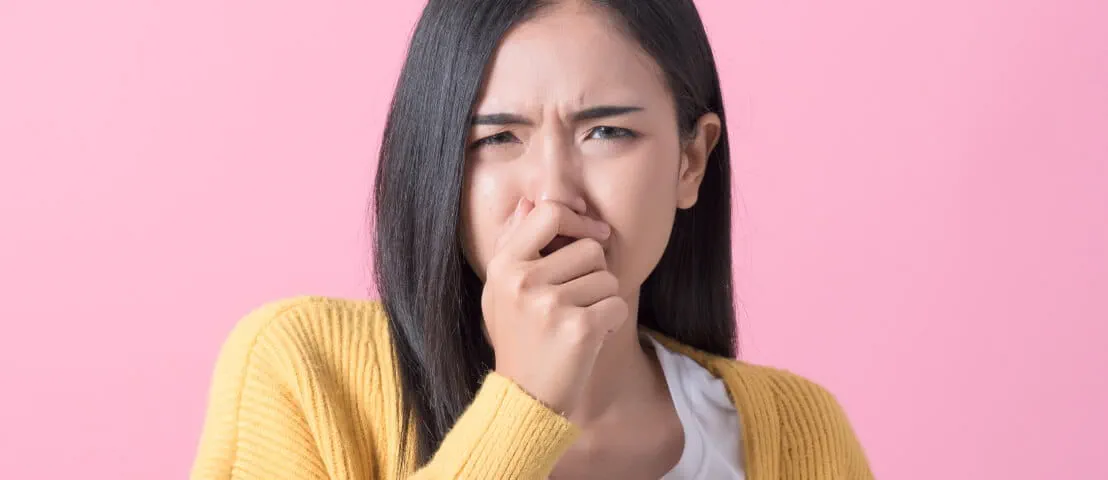 A person plugging their nose while grimacing.