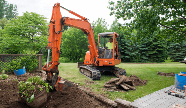Landscape contractor in earth mover digging soil at construction site