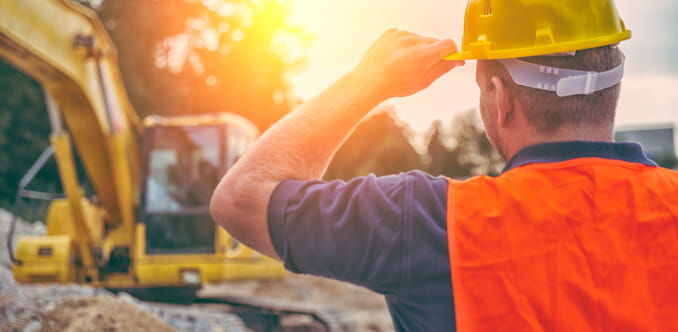 A person wearing safety gear, overseeing a safe excavation on a construction site.