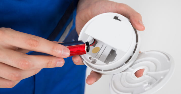 Close-up of hand holding smoke detector battery