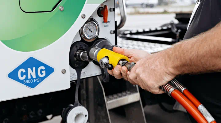 A person connecting a hose to a Compressed Natural Gas (CNG) pump