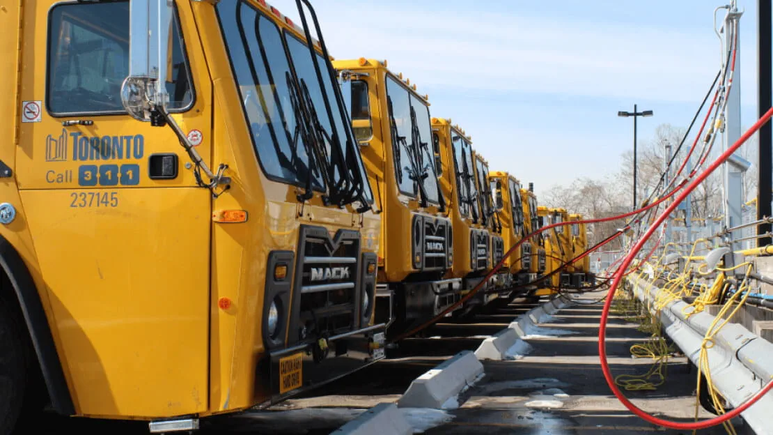 Six trucks in the City of Toronto’s waste collection fleet, parked in an exterior lot.