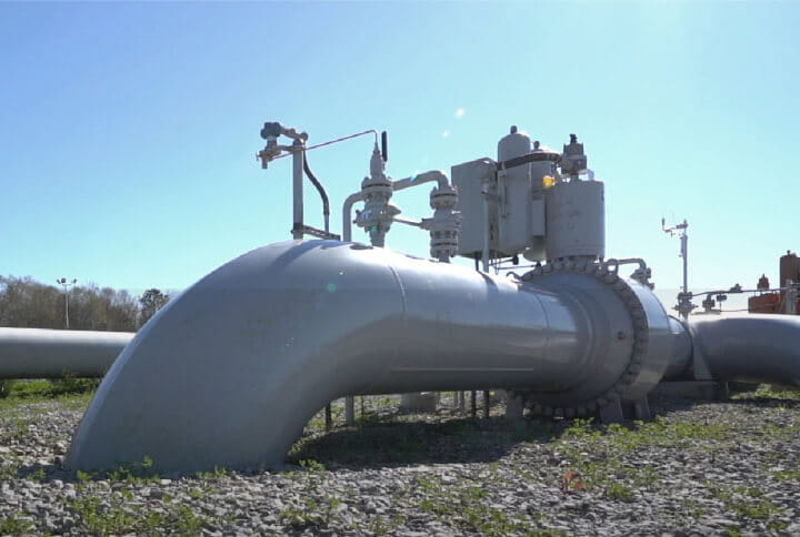 Photo of a carbon capture pipeline at surface level, running below ground. 