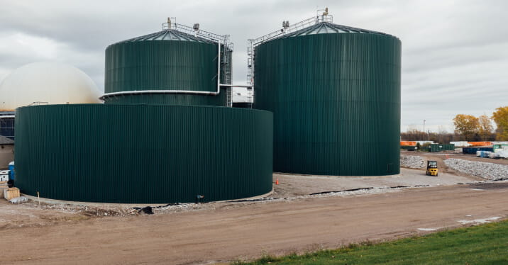 Outdoor view of dark green anaerobic digesters at StormFisher biogas facility in London, Ontario. 
