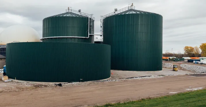 Outdoor view of dark green anaerobic digesters at StormFisher biogas facility in London, Ontario. 