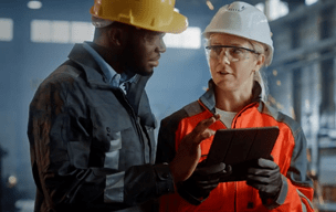 Two people reviewing a tablet in a factory.