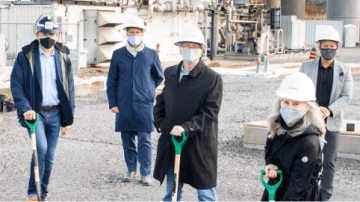 Wearing masks and holding shovels, five people break ground on a new development.