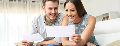 Happy couple looking and checking bills at home 