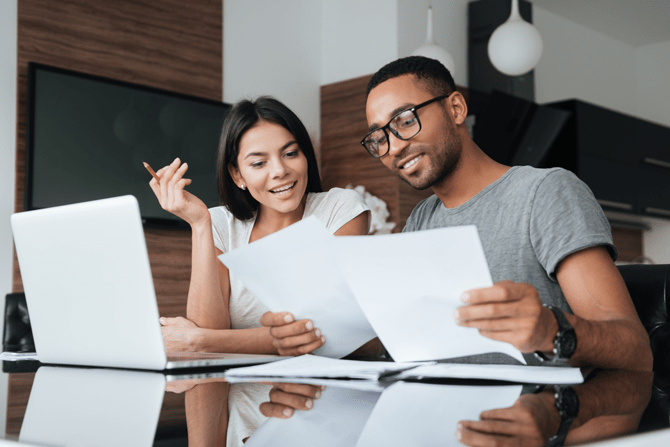 Cheerful loving young couple using laptop and analyzing finances