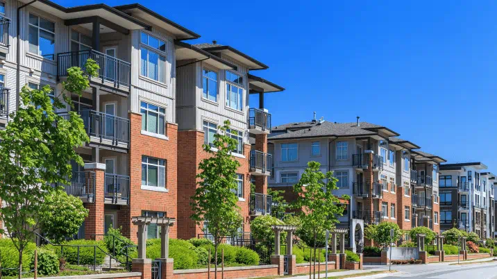 Street level view of a four storey modern condominium development on a clear day. 