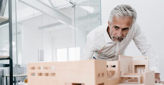 Older man examining an architectural model in an office