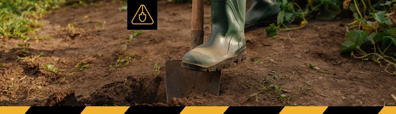 A person wearing boots and standing on a shovel