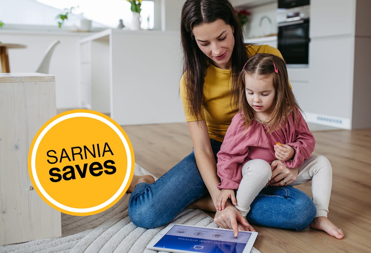 A woman sitting on the floor with her daughter in their cozy home watching ipad.