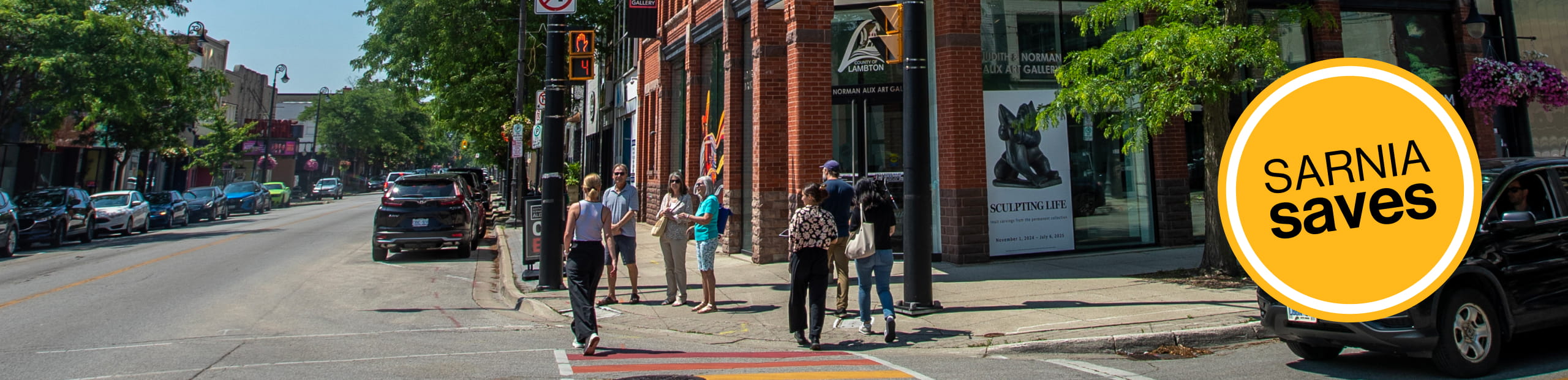 People on a sidewalk with Sarnia Saves icon on the right.