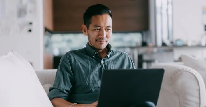A person sitting on a couch using a computer.